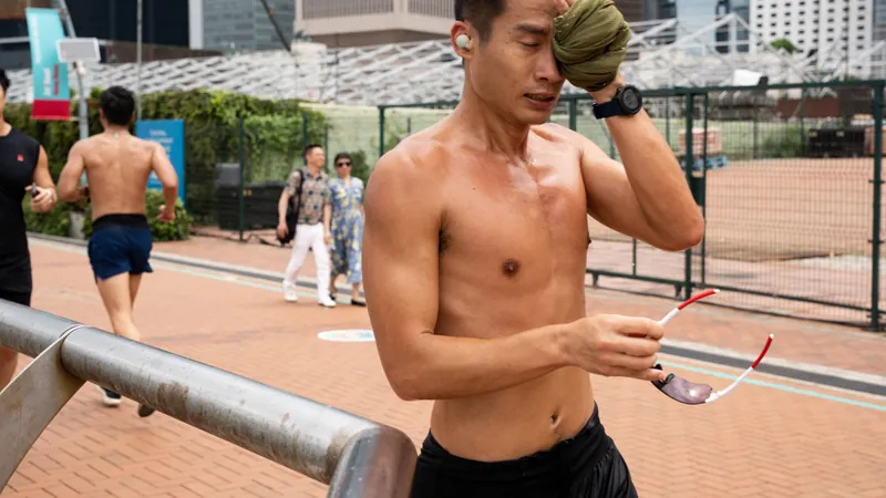 Runner wiping sweat from his face during a hot, humid run in the city