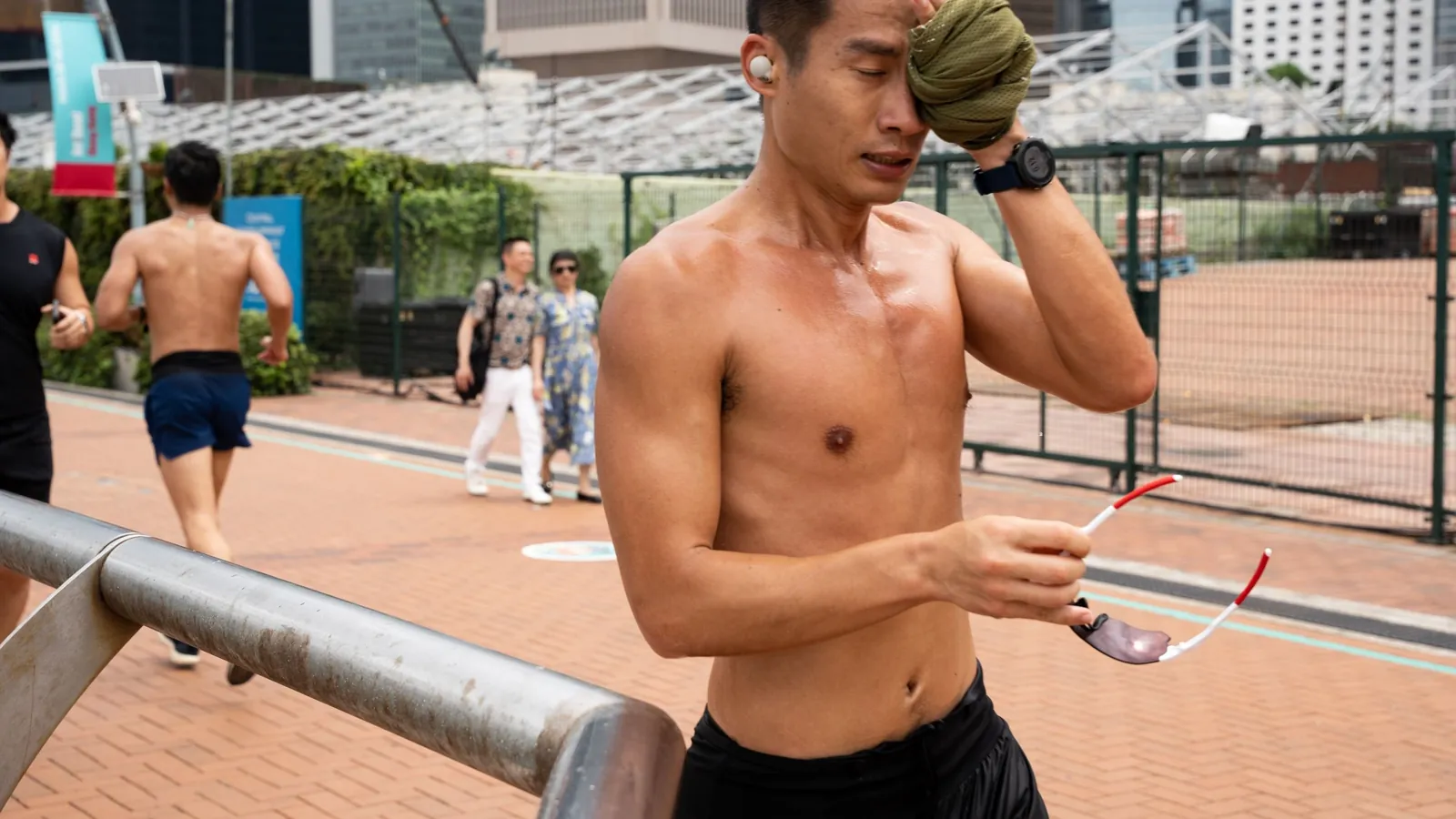 Runner wiping sweat from his face during a hot, humid run in the city
